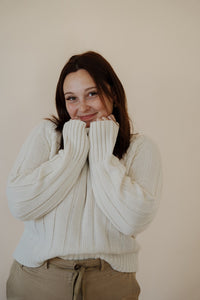front view of model wearing the every moment sweater in the color ivory. model has the sweater paired with the in another life skirt.