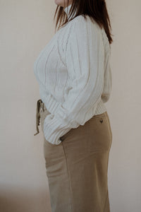 side view of model wearing the every moment sweater in the color ivory. model has the sweater paired with the in another life skirt.