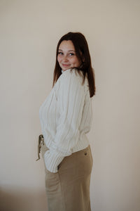 side view of model wearing the every moment sweater in the color ivory. model has the sweater paired with the in another life skirt.