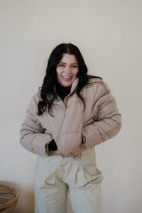 front view of model wearing the time after time puffer in the color khaki. model has the puffer paired with the all along top in the color black and the oakland chinos.