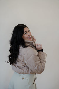 back view of model wearing the time after time puffer in the color khaki. model has the puffer paired with the all along top in the color black and the oakland chinos.