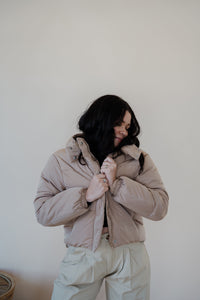 front view of model wearing the where it all began puffer in the color khaki. model has the puffer paired with the all along top in the color black and the oakland chinos.