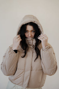 front view of model wearing the where it all began puffer in the color khaki. model has the puffer paired with the all along top in the color black and the oakland chinos.