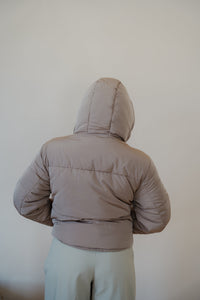 back view of model wearing the where it all began puffer in the color khaki. model has the puffer paired with the all along top in the color black and the oakland chinos.