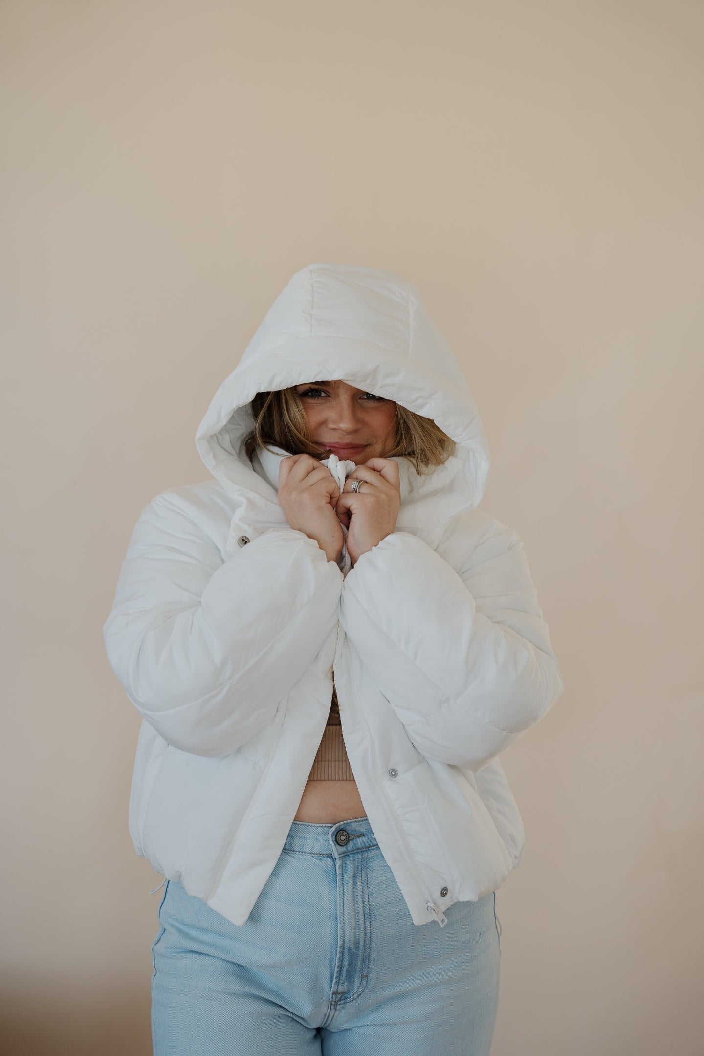 front view of model wearing the where it all began puffer in the color ivory. model has the puffer paired with the all along top in the color almond and the camden denim.
