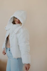 side view of model wearing the where it all began puffer in the color ivory. model has the puffer paired with the all along top in the color almond and the camden denim.