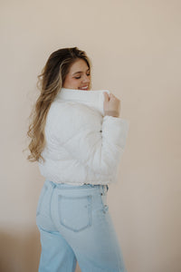 side view of model wearing the time after time puffer in the color ivory. model has the puffer paired with the all along top in the color almond and the camden denim.