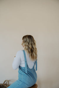 back view of model wearing the clara denim jumpsuit in denim.