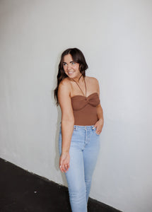 model wearing the think of me top in the color brown. model has the top paired with a pair of light wash denim.