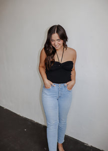 model wearing the think of me top in the color black. model has the top paired with a pair of light wash denim.