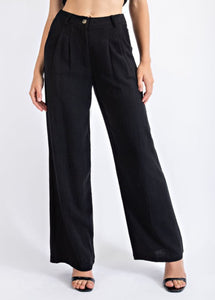 Photo of model wearing the Chelsea Linen Trousers in the color black paired with black heels. Photo is taken from the torso down.