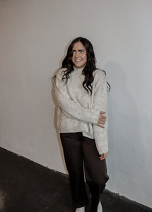 model wearing the late night talking sweater in the color oatmeal. model has the sweater paired with the logan trousers in the color espresso + a pair of platform sneakers.