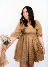 Load image into Gallery viewer, front view of model wearing the familiar glow dress with one hand pinching the side of the dress and other other holding out a bunch of flowers