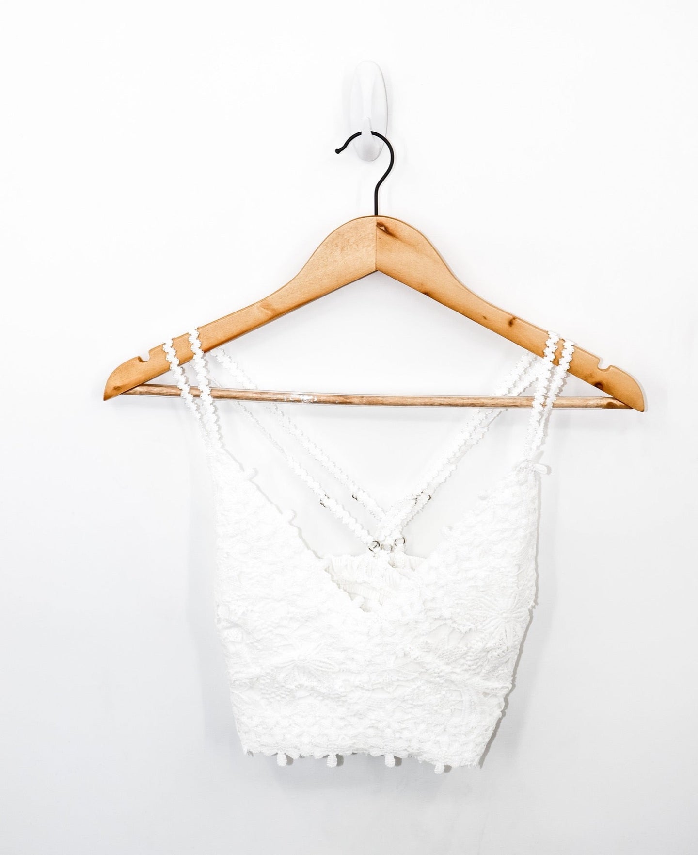 front view of always knew floral lace bralette in the color white pictured on a wooden hanger with a white backdrop
