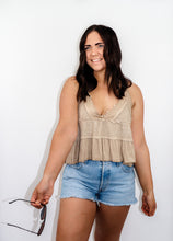 Load image into Gallery viewer, model wearing the moving on top in the color taupe paired with light denim shorts; model is holding a pair of sunglasses in one hand