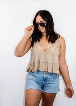 Load image into Gallery viewer, model wearing the moving on top in the color taupe paired with light denim shorts; model is wearing a pair of sunglasses with one hand pinching the frames