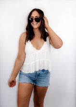 Load image into Gallery viewer, model wearing the moving on top in the color white paired with light denim shorts; model is wearing a pair of sunglasses and has one hand in her hair