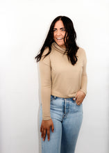 Load image into Gallery viewer, model wearing the by your side top in the color taupe paired with a pair of lightwash denim. model is standing with one hand in her pocket with her thumb through a belt loop and the other hand resting on her thigh. model is smiling and looking to the side.