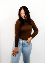 Load image into Gallery viewer, model wearing the by your side top in the color espresso paired with a pair of lightwash denim. model is standing with one hand in her pocket with her thumb through a belt loop and the other hand resting on her thigh. model is smiling and looking down towards the ground in front of her.