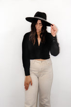 Load image into Gallery viewer, model wearing the all this time top paired with a pair of cream colored denim jeans and a black rancher style hat. model is looking downward, and resting one hand on her hat and the other on her thigh.