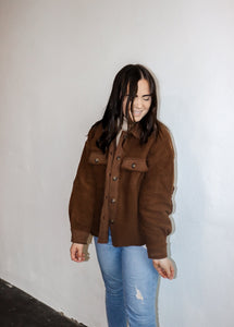 model wearing the never look back jacket in the color brown. model has the jacket paired with the can't get enough top in the color oatmeal and a pair of denim.