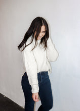 Load image into Gallery viewer, model wearing the patiently waiting sweater in the color ivory. model has the sweater paired with a pair of black denim.