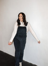 Load image into Gallery viewer, model wearing the sweet disposition overalls in the color charcoal. model has the overalls paired with the by your side top in the color cream.