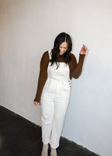 Load image into Gallery viewer, model wearing the sweet disposition overalls in the color cream. model has the overalls paired with the by your side top in the color espresso.