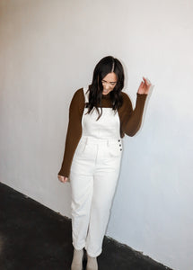 model wearing the sweet disposition overalls in the color cream. model has the overalls paired with the by your side top in the color espresso.