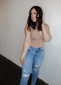 model wearing the stay the same top in the color dark taupe. model has the top paired with a pair of high-waisted distressed denim.