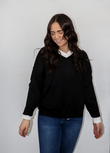 Load image into Gallery viewer, model wearing the state of grace sweater in the color black. model has the sweater paired with the play by my rules top in the color white and a pair of high-waisted dark-wash denim.