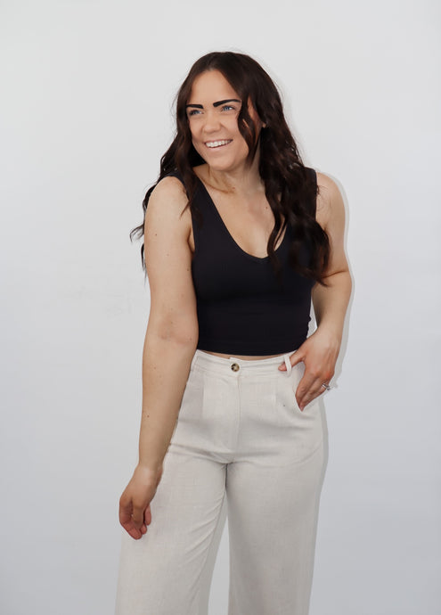 model wearing the stay the same top in the color black. model has the top paired with the chelsea linen trousers in the color oatmeal.