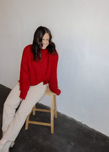 Load image into Gallery viewer, model wearing the patiently waiting sweater in the color red. model has the sweater paired with the siena denim.