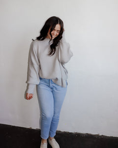 model wearing the eighth avenue tunic sweater in the color grey. model has the top paired with a pair of lightwash denim.