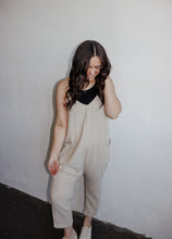 Load image into Gallery viewer, model wearing the never felt this way jumpsuit in the color parchment. model hs the jumpsuit paaired with the these days top in the color black and a pair of platform sneakers.