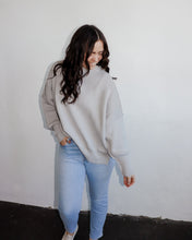 Load image into Gallery viewer, model wearing the eighth avenue tunic sweater in the color grey. model has the top paired with a pair of lightwash denim.