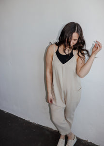 model wearing the never felt this way jumpsuit in the color parchment. model hs the jumpsuit paaired with the these days top in the color black and a pair of platform sneakers.