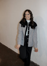 Load image into Gallery viewer, model wearing the never say never jacket in the color black/charcoal. model has the jacket paired with the all along sweater vest and the logan trousers in the color black.