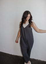 Load image into Gallery viewer, model wearing the never felt this way jumpsuit in the color washed black. model has the jumpsuit paired with the these days top in the color chalk and a pair of platform sneakers.