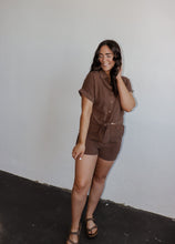 Load image into Gallery viewer, model wearing the coastline top in the color cocoa. model has the top paired with the coastline shorts in the color cocoa and a pair of flatbed sandals.
