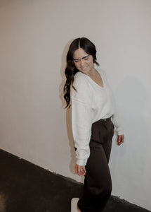 model wearing the play it cool sweater. model has the top paired with the logan trousers in the color espresso and a pair of platform sneakers.