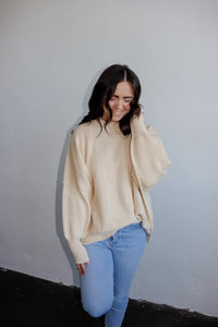 model wearing the eighth avenue tunic sweater in the color ivory. model has the top paired with a pair of lightwash denim.