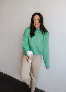 model wearing the patiently waiting sweater in the color jade. model has the sweater paired with the siena denim.
