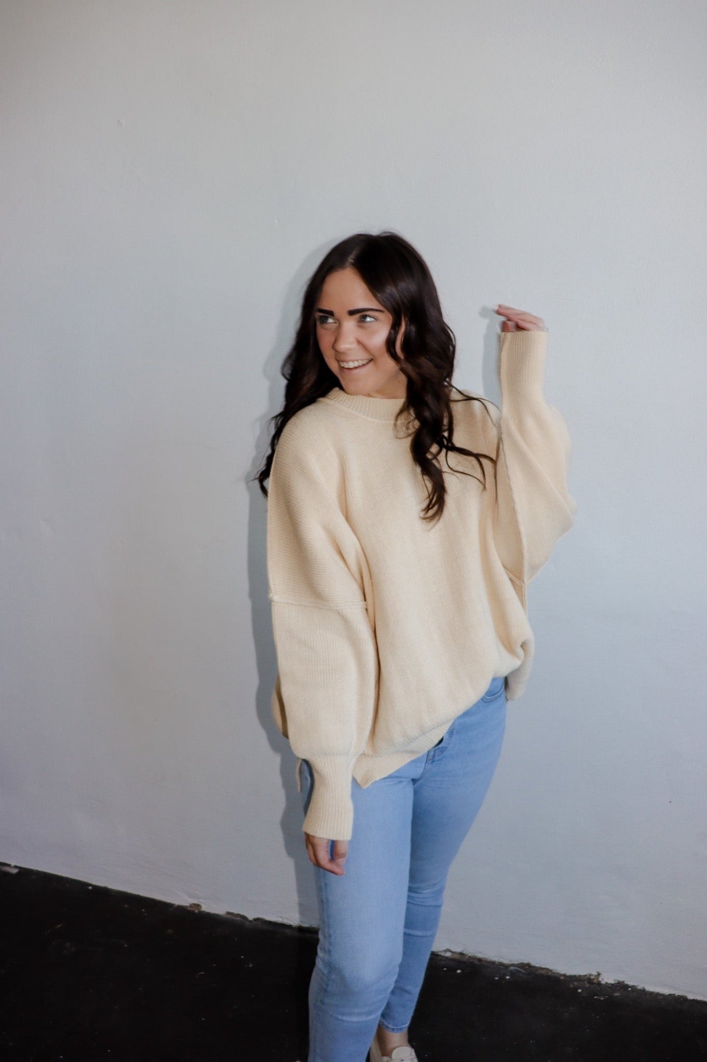 model wearing the eighth avenue tunic sweater in the color ivory. model has the top paired with a pair of lightwash denim.