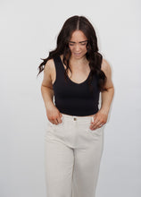 Load image into Gallery viewer, model wearing the stay the same top in the color black. model has the top paired with the chelsea linen trousers in the color oatmeal.