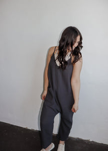 model wearing the never felt this way jumpsuit in the color washed black. model has the jumpsuit paired with the these days top in the color chalk and a pair of platform sneakers.