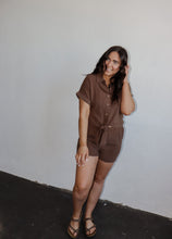 Load image into Gallery viewer, model wearing the coastline top in the color cocoa. model has the top paired with the coastline shorts in the color cocoa and a pair of flatbed sandals.
