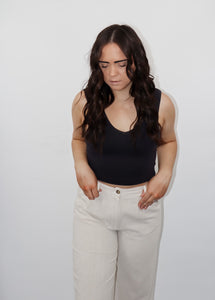 model wearing the stay the same top in the color black. model has the top paired with the chelsea linen trousers in the color oatmeal.