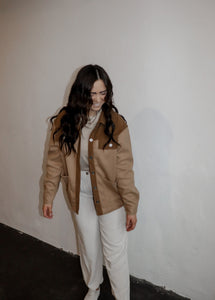 model wearing the never say never jacket in the color camel/taupe. model has the jacket paired with the by your side top in the color taupe and the chelsea linen trousers in the color oatmeal.